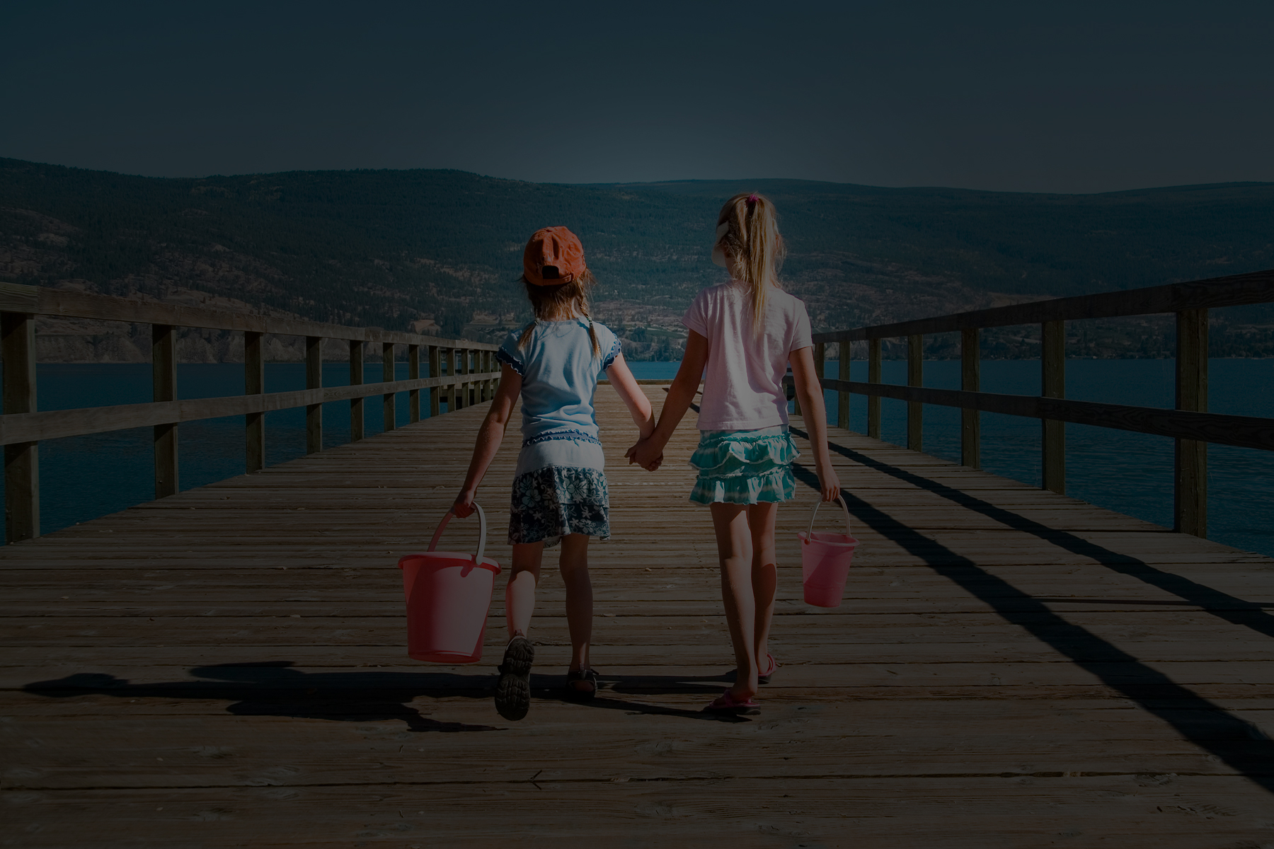 Two children walking together on a sunlit pier